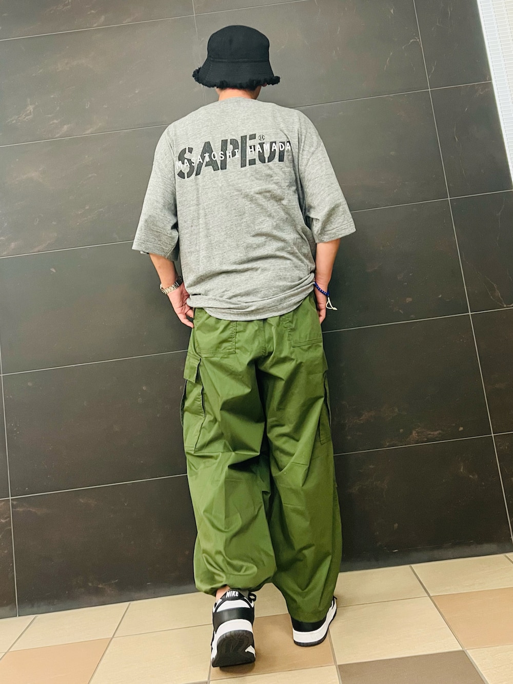 グレー系のTシャツ/カットソー、グリーン系のカーゴパンツ、ブラック系のスニーカーを着用したメンズの夏コーディネートの2枚目の写真