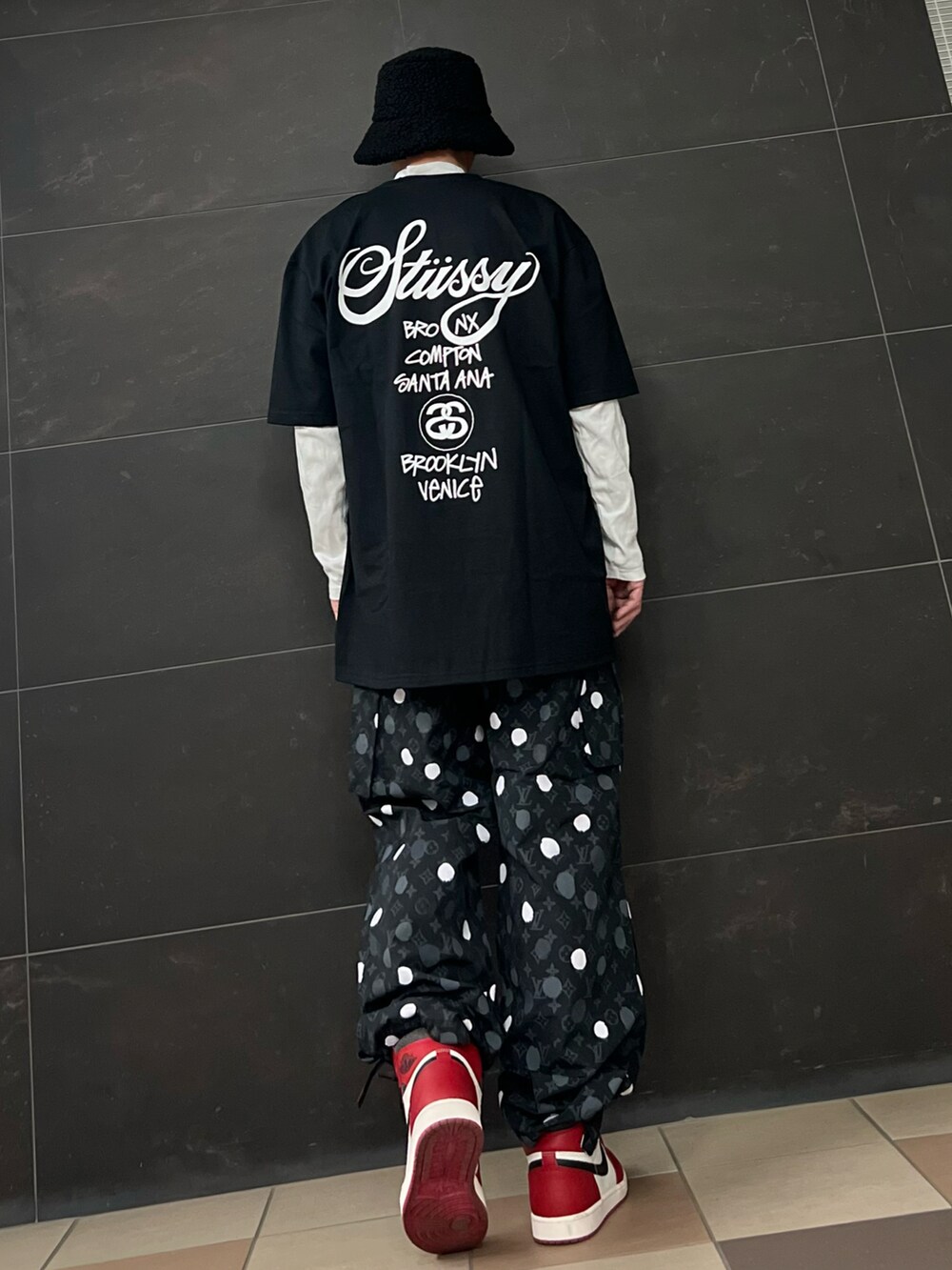 レッド系のスニーカー、ブラック系のカーゴパンツ、ブラック系のTシャツ/カットソーを着用したメンズの春コーディネートの2枚目の写真