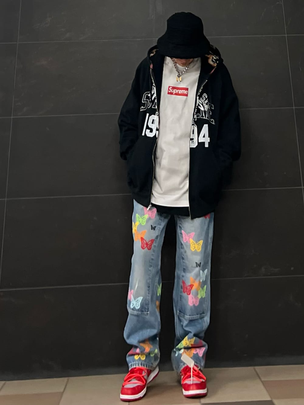 ブルー系のデニムパンツ、レッド系のスニーカー、ブラック系のパーカーを着用したメンズの春コーディネートの2枚目の写真