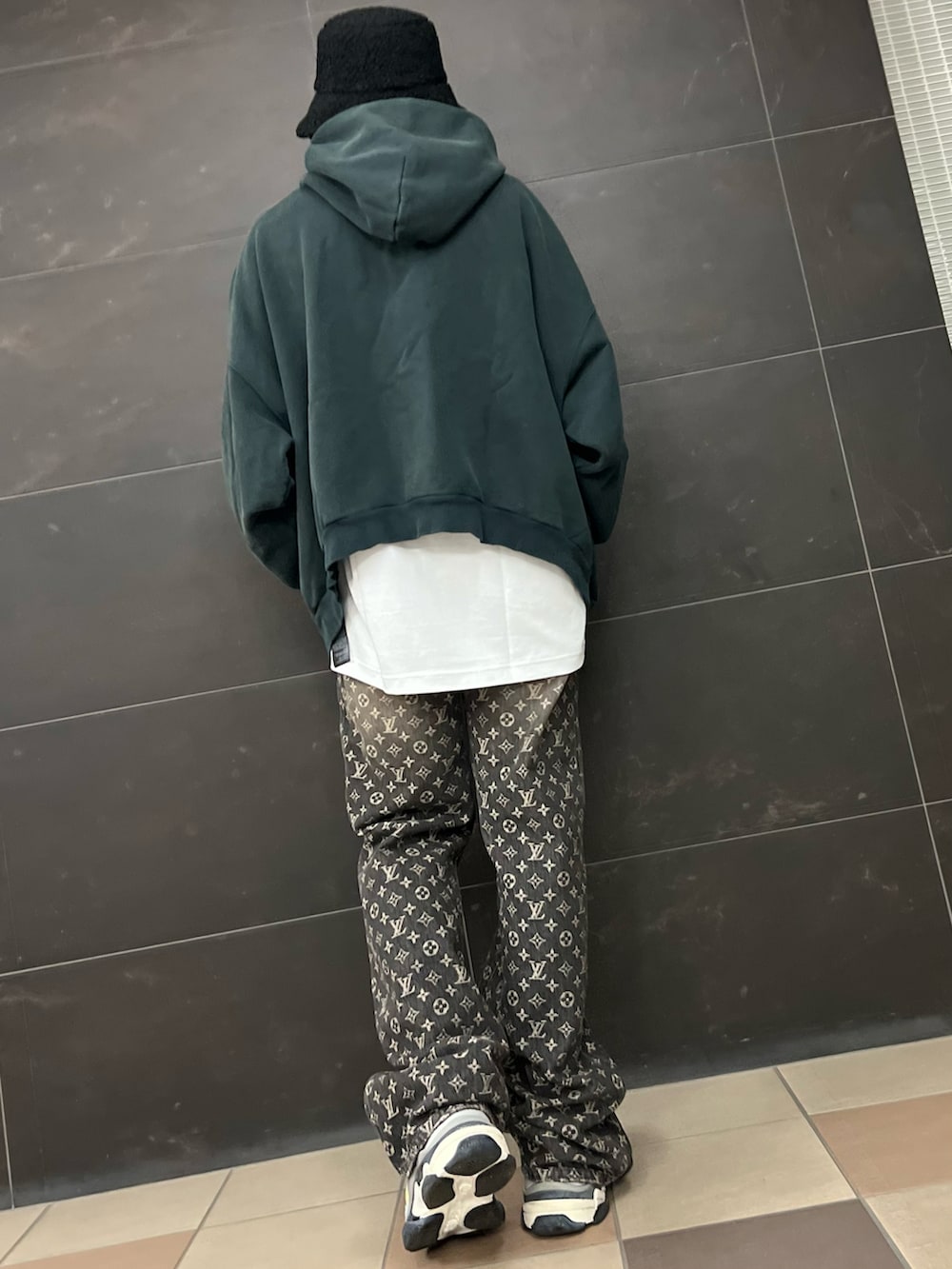 ブラック系のデニムパンツ、グリーン系のパーカー、イエロー系のスニーカーを着用したメンズの冬コーディネートの4枚目の写真