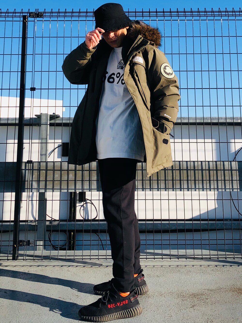 グリーン系のダウンジャケット/コート、ホワイト系のTシャツ/カットソー、ブラック系のスウェットパンツを着用したメンズの冬コーディネートの4枚目の写真