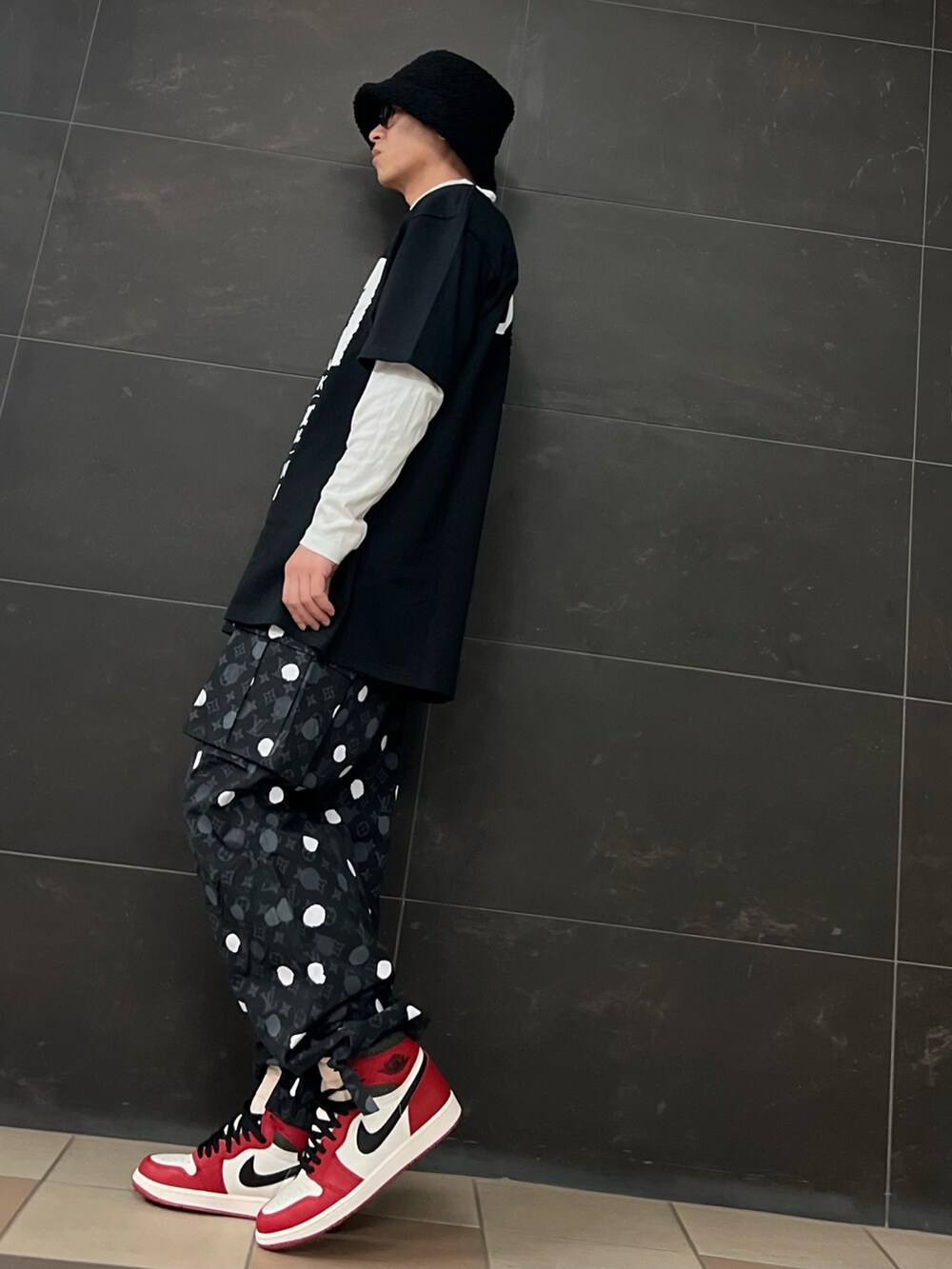 レッド系のスニーカー、ブラック系のカーゴパンツ、ブラック系のTシャツ/カットソーを着用したメンズの春コーディネートの3枚目の写真