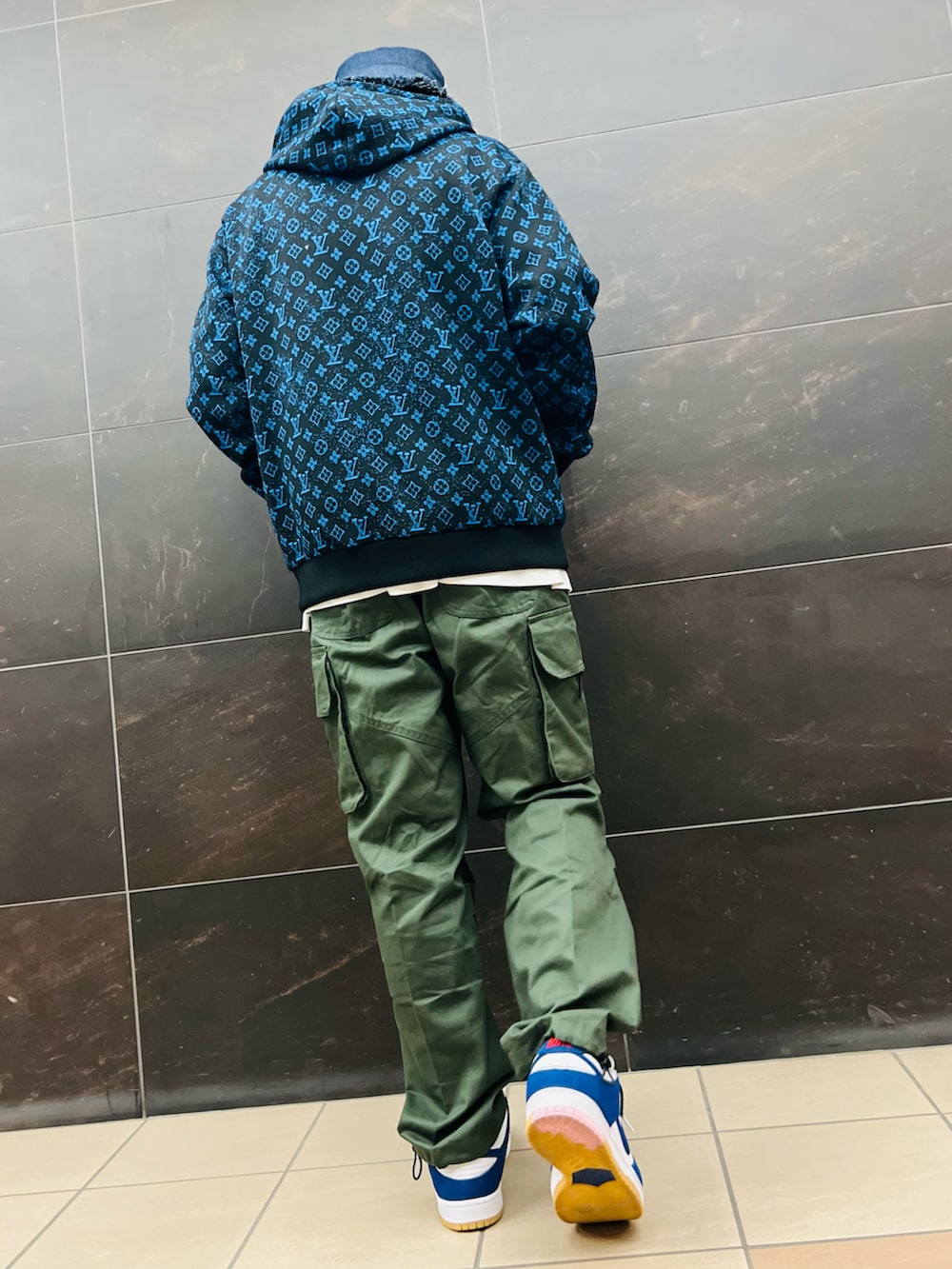 グリーン系のカーゴパンツ、ブルー系のパーカー、ブルー系のスニーカーを着用したメンズの秋コーディネートの3枚目の写真