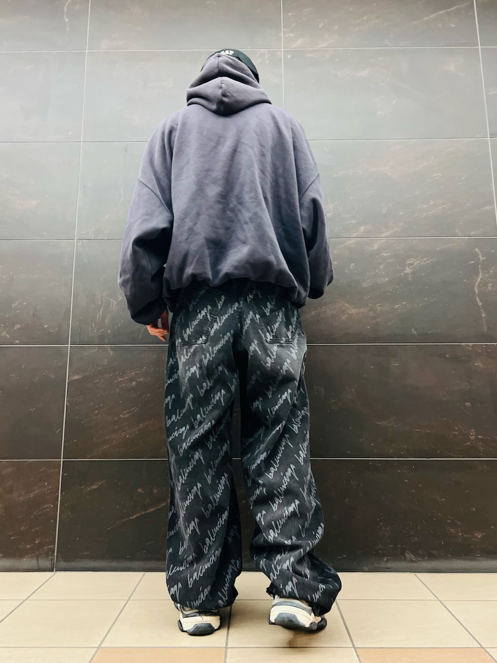 ブラック系のデニムパンツ、イエロー系のスニーカー、グレー系のパーカーを着用したメンズの秋コーディネートの3枚目の写真