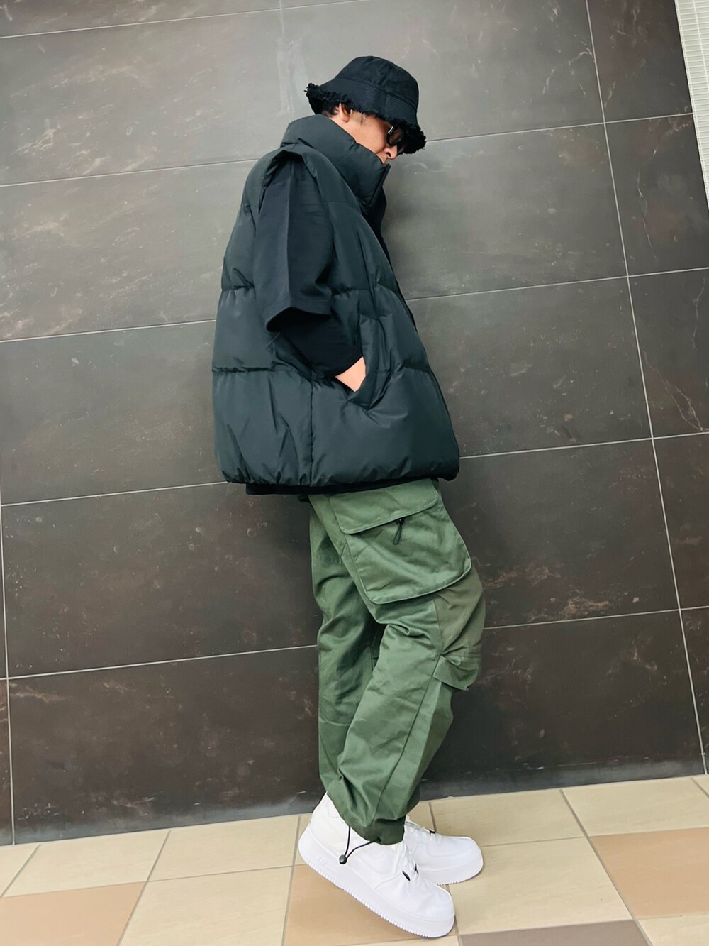 ブラック系のダウンベスト、ブラック系のTシャツ/カットソー、グリーン系のカーゴパンツを着用したメンズの秋コーディネートの2枚目の写真