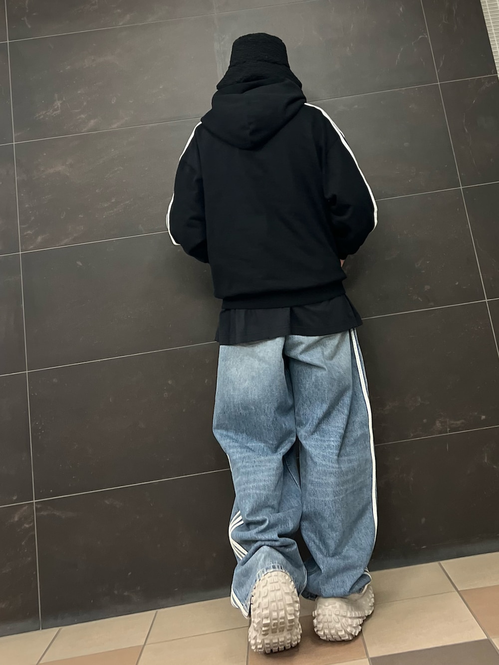 ブルー系のデニムパンツ、ブラック系のパーカー、ベージュ系のスニーカーを着用したメンズの春コーディネートの3枚目の写真