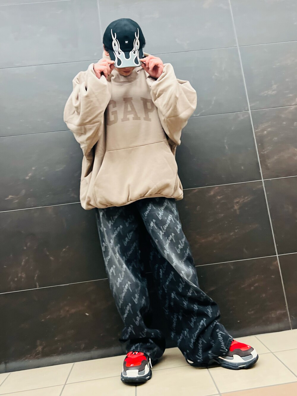 ベージュ系のパーカー、ブラック系のデニムパンツ、レッド系のスニーカーを着用したメンズの秋コーディネートの2枚目の写真