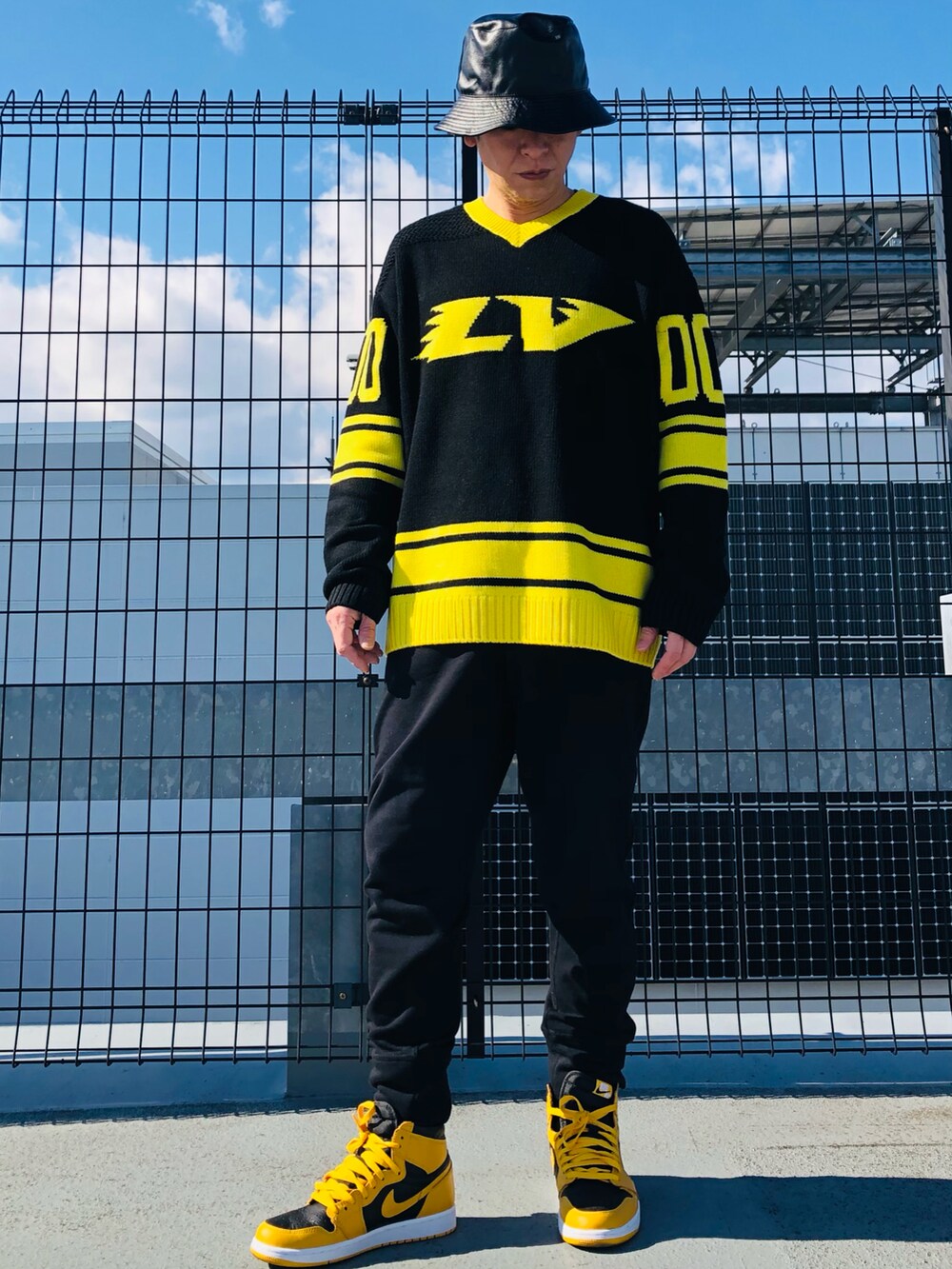 イエロー系のニット/セーター、ブラック系のスウェットパンツ、イエロー系のスニーカーを着用したメンズの春コーディネートの4枚目の写真