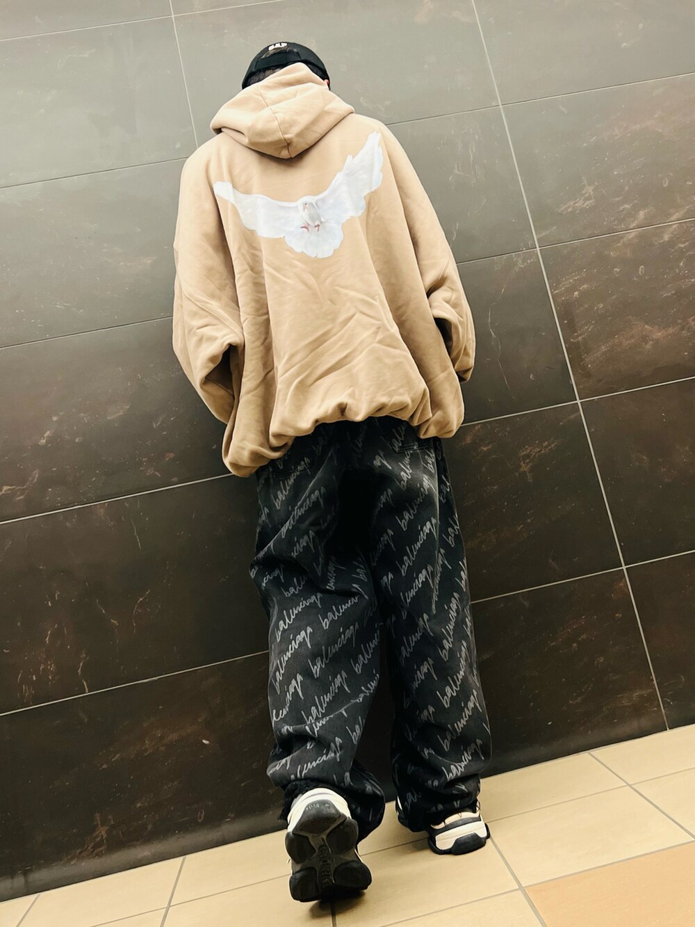 ベージュ系のパーカー、ブラック系のデニムパンツ、レッド系のスニーカーを着用したメンズの秋コーディネートの4枚目の写真