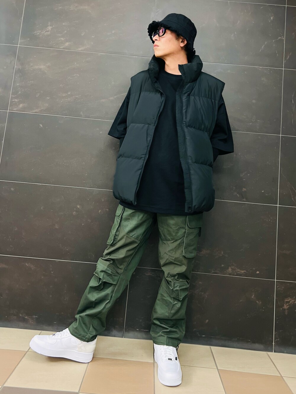 ブラック系のダウンベスト、ブラック系のTシャツ/カットソー、グリーン系のカーゴパンツを着用したメンズの秋コーディネートの4枚目の写真