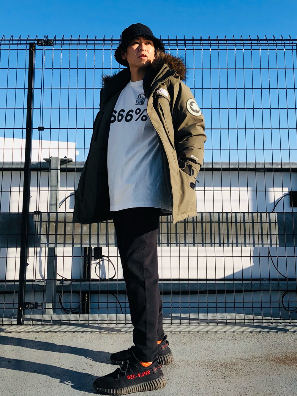 グリーン系のダウンジャケット/コート、ホワイト系のTシャツ/カットソー、ブラック系のスウェットパンツを着用したメンズの冬コーディネートの3枚目の写真