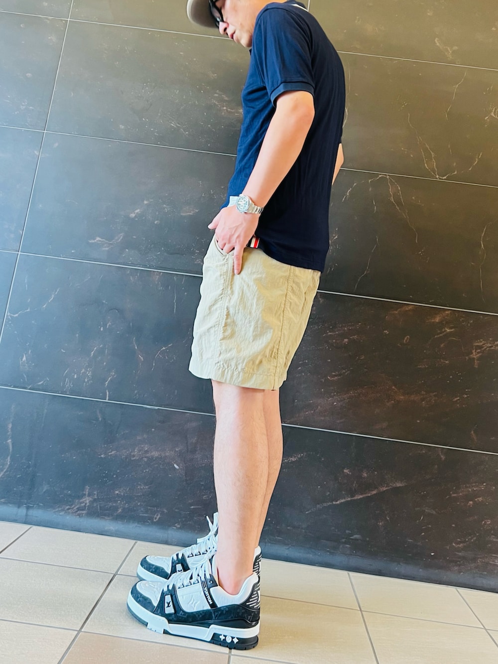 ブラック系のスニーカー、ベージュ系のその他パンツ、ブルー系のポロシャツを着用したメンズの夏コーディネートの3枚目の写真