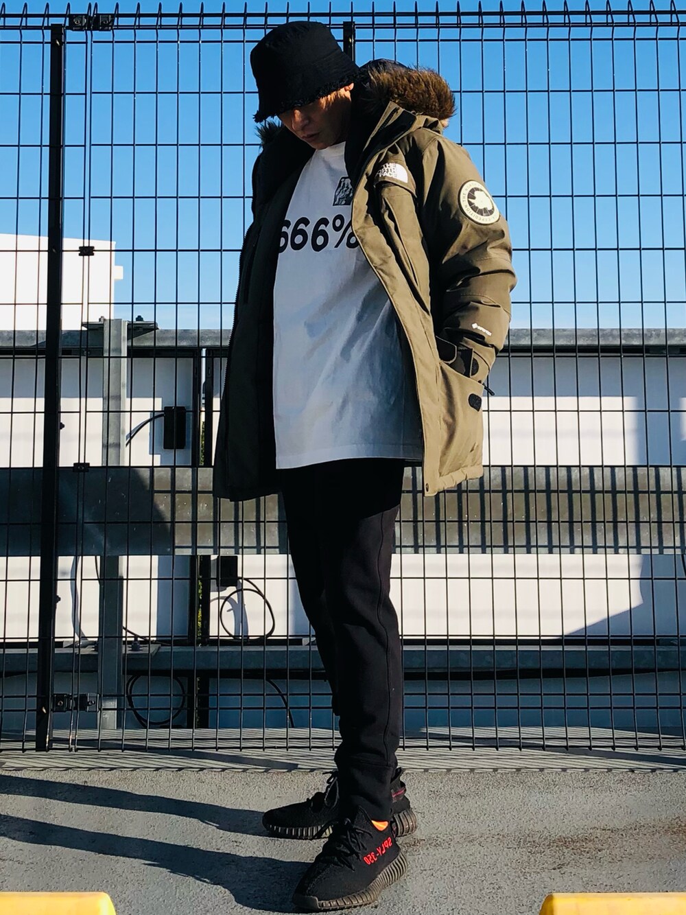 グリーン系のダウンジャケット/コート、ホワイト系のTシャツ/カットソー、ブラック系のスウェットパンツを着用したメンズの冬コーディネートの2枚目の写真