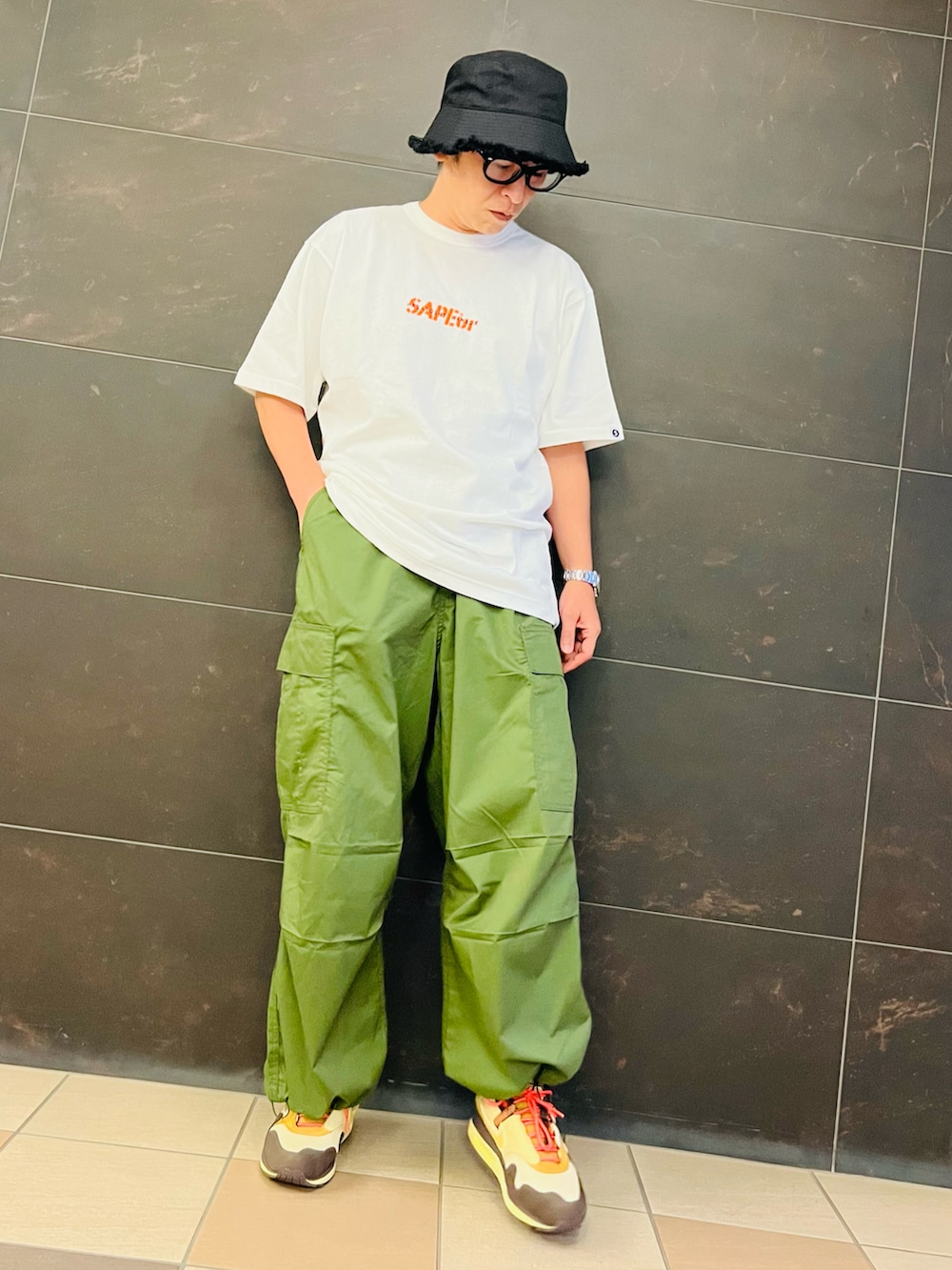 ブラウン系のスニーカー、ホワイト系のTシャツ/カットソー、グリーン系のカーゴパンツを着用したメンズの夏コーディネートの2枚目の写真