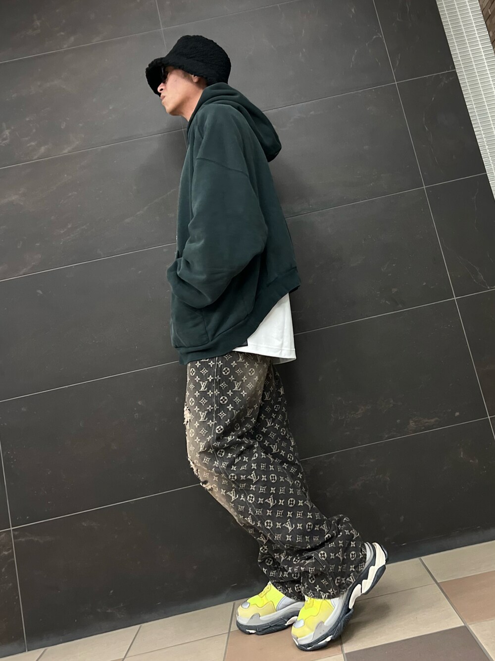 ブラック系のデニムパンツ、グリーン系のパーカー、イエロー系のスニーカーを着用したメンズの冬コーディネートの3枚目の写真