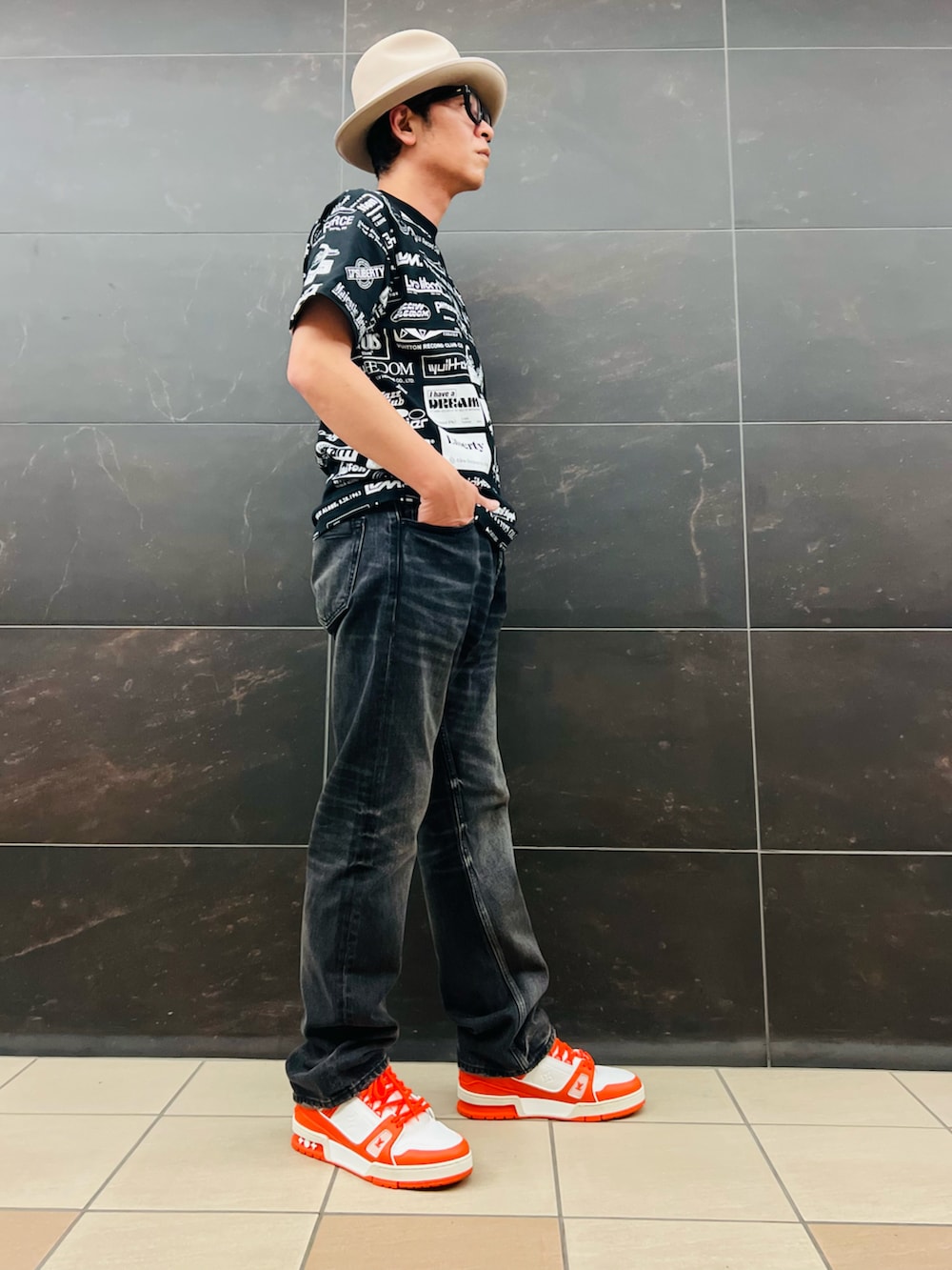 ブラック系のTシャツ/カットソー、ブラック系のデニムパンツ、オレンジ系のスニーカーを着用したメンズの夏コーディネートの2枚目の写真