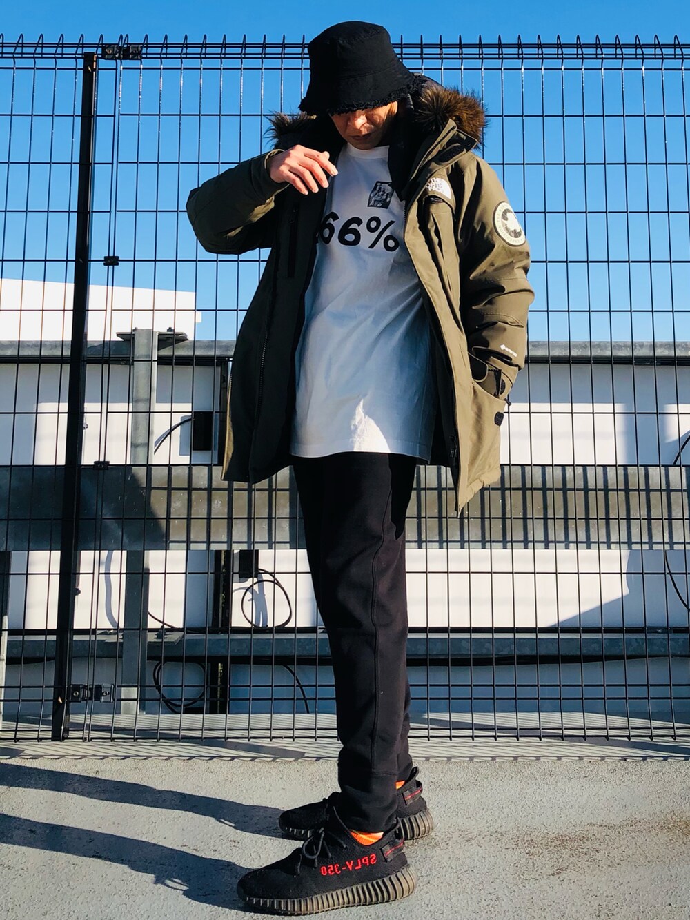 グリーン系のダウンジャケット/コート、ホワイト系のTシャツ/カットソー、ブラック系のスウェットパンツを着用したメンズの冬コーディネートの5枚目の写真