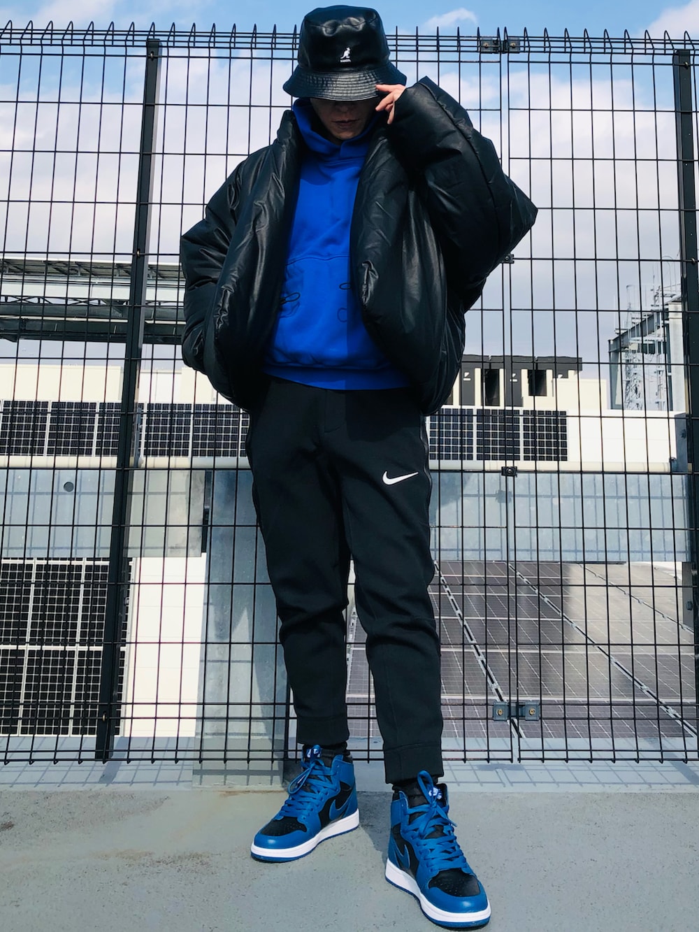 ブラック系のダウンジャケット/コート、ブルー系のパーカー、ブラック系のスウェットパンツを着用したメンズの春コーディネートの2枚目の写真