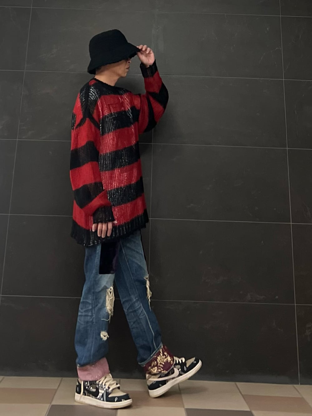 ブラック系のニット/セーター、ブルー系のデニムパンツ、ブラック系のスニーカーを着用したメンズの秋コーディネートの2枚目の写真