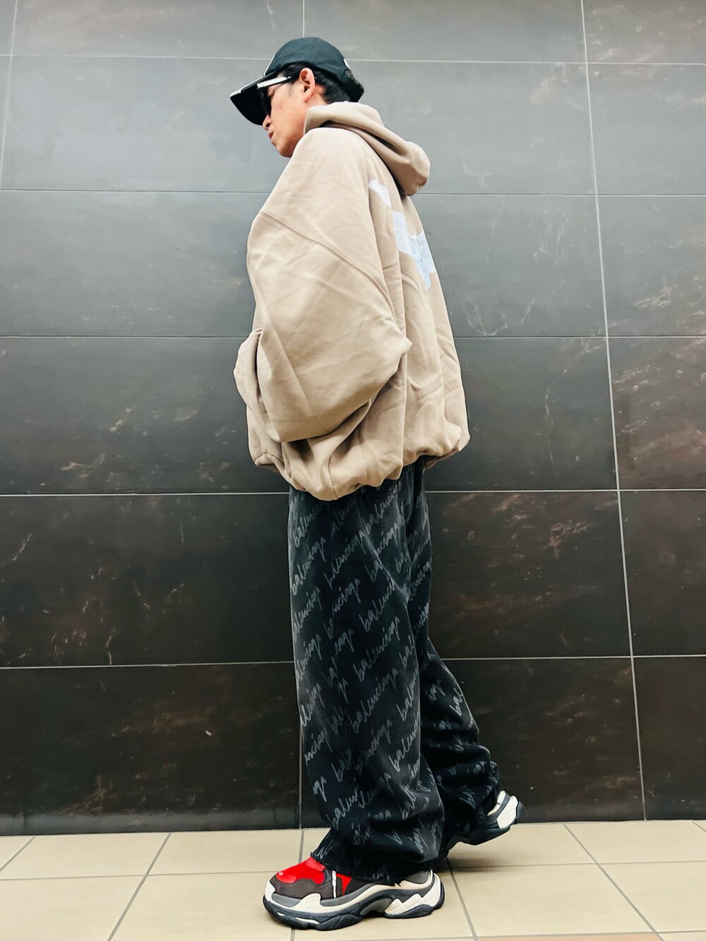 ベージュ系のパーカー、ブラック系のデニムパンツ、レッド系のスニーカーを着用したメンズの秋コーディネートの3枚目の写真