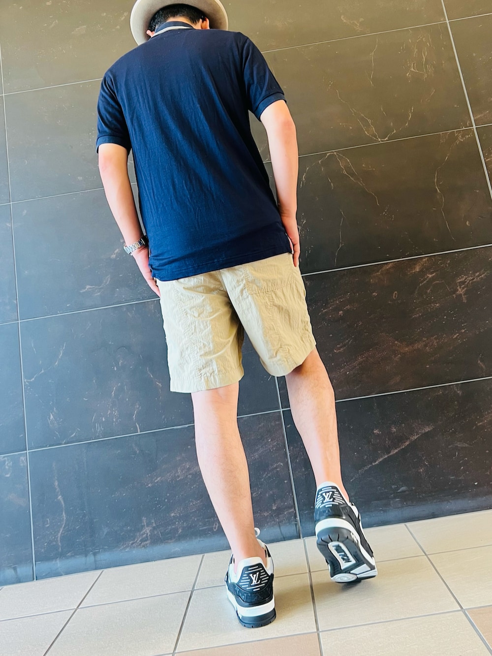 ブラック系のスニーカー、ベージュ系のその他パンツ、ブルー系のポロシャツを着用したメンズの夏コーディネートの4枚目の写真