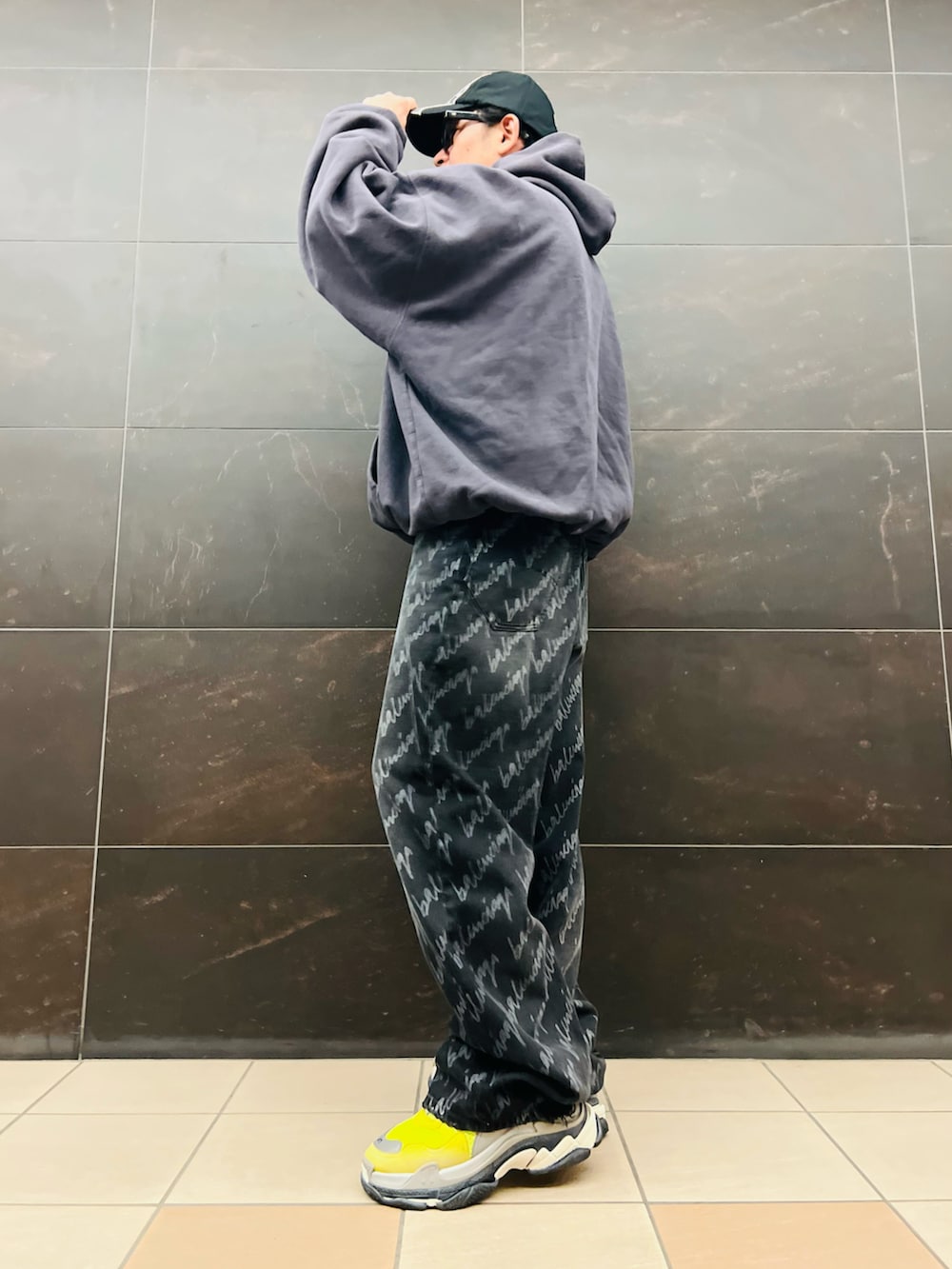 ブラック系のデニムパンツ、イエロー系のスニーカー、グレー系のパーカーを着用したメンズの秋コーディネートの2枚目の写真