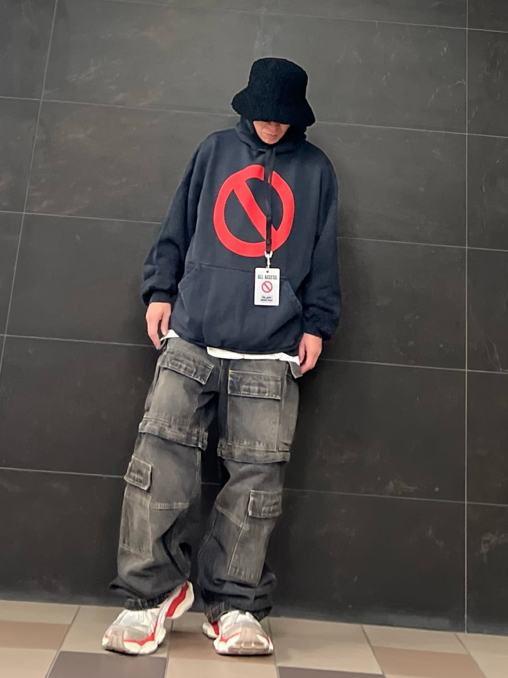 ブラック系のデニムパンツ、ブラック系のパーカー、ホワイト系のスニーカーを着用したメンズの秋コーディネートの2枚目の写真