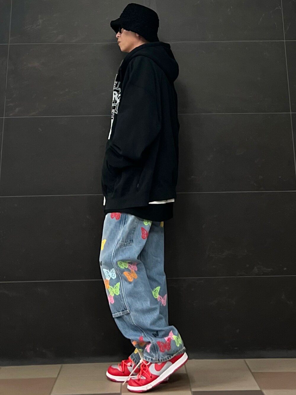 ブルー系のデニムパンツ、レッド系のスニーカー、ブラック系のパーカーを着用したメンズの春コーディネートの4枚目の写真
