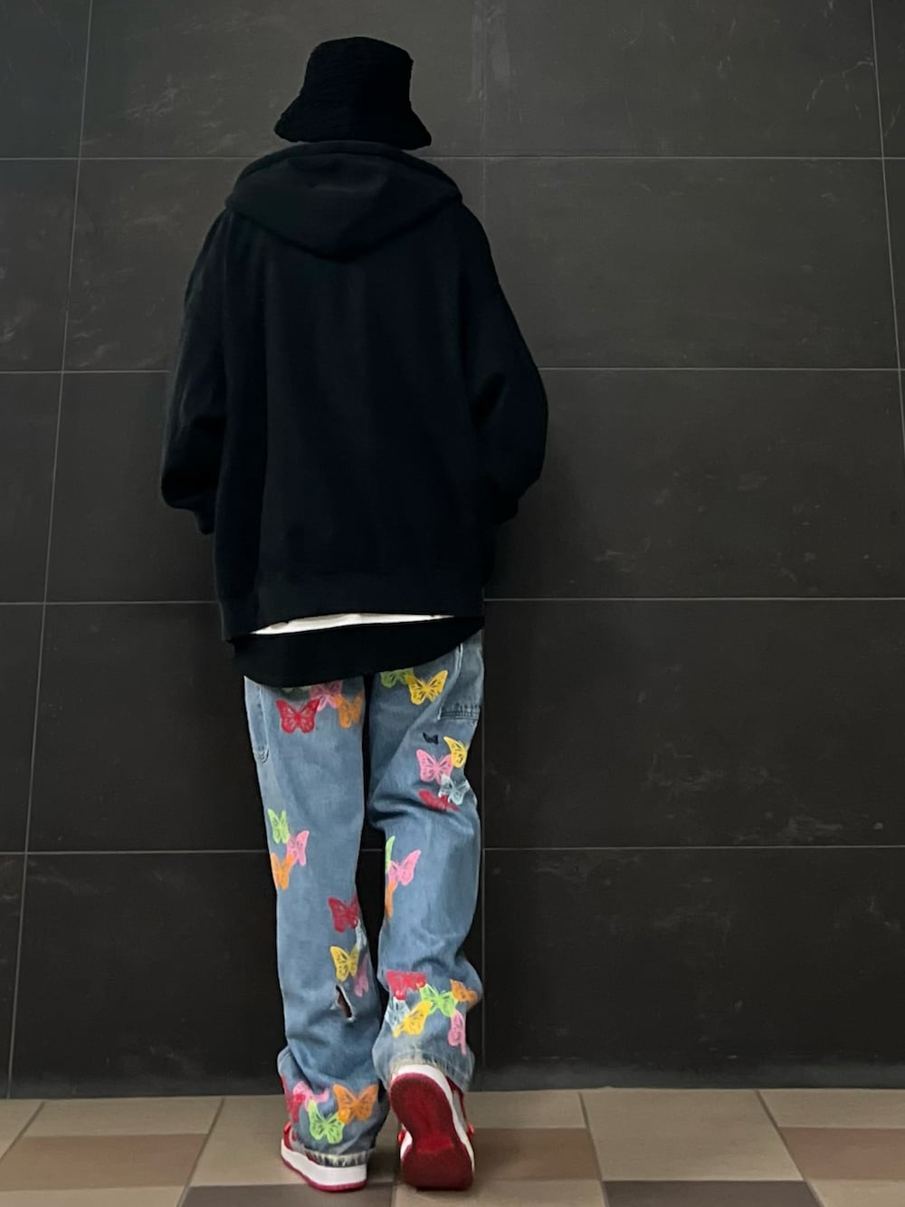 ブルー系のデニムパンツ、レッド系のスニーカー、ブラック系のパーカーを着用したメンズの春コーディネートの3枚目の写真