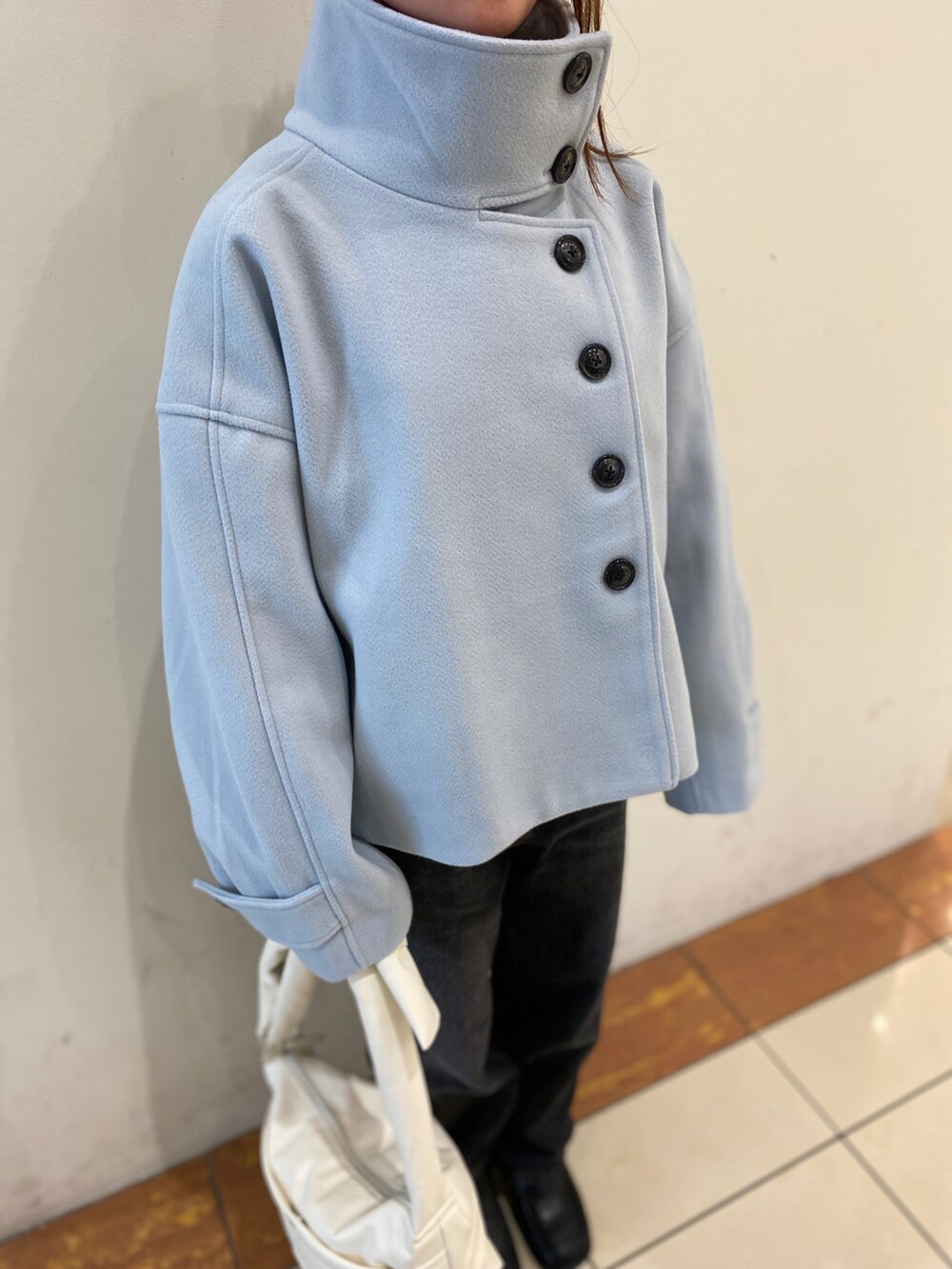 ブルー系のその他アウター、ブラック系のデニムパンツ、ホワイト系のハンドバッグを着用したレディースの秋コーディネートの2枚目の写真