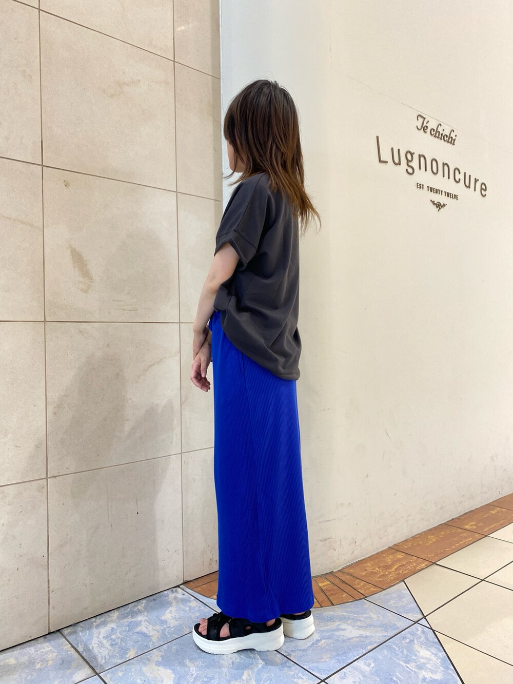 グレー系のTシャツ/カットソー、ブルー系のスカート、ブラック系のサンダルを着用したレディースの夏コーディネートの2枚目の写真