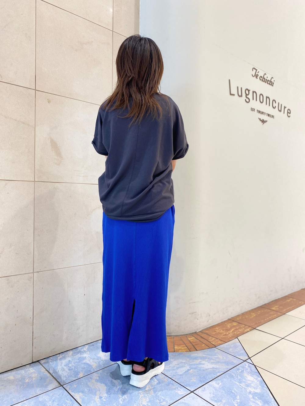 グレー系のTシャツ/カットソー、ブルー系のスカート、ブラック系のサンダルを着用したレディースの夏コーディネートの3枚目の写真