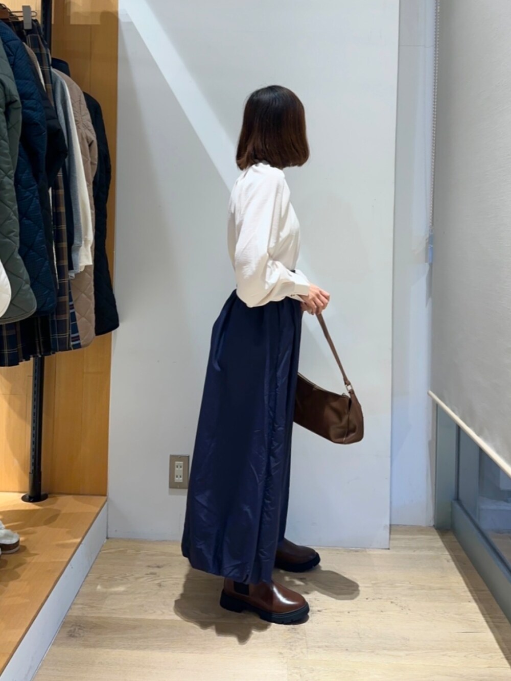 ホワイト系のシャツ/ブラウス、ブルー系のスカート、ブラウン系のハンドバッグを着用したレディースの冬コーディネートの2枚目の写真