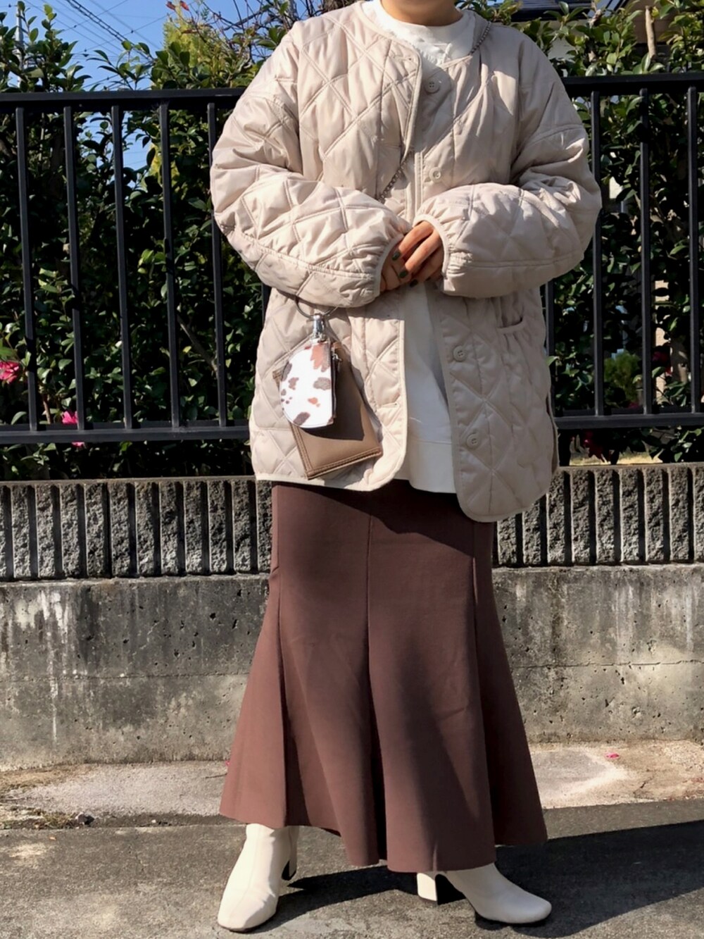 ホワイト系のスウェット、ブラウン系のショルダーバッグ、ブラウン系のスカートを着用したレディースの秋コーディネートの2枚目の写真