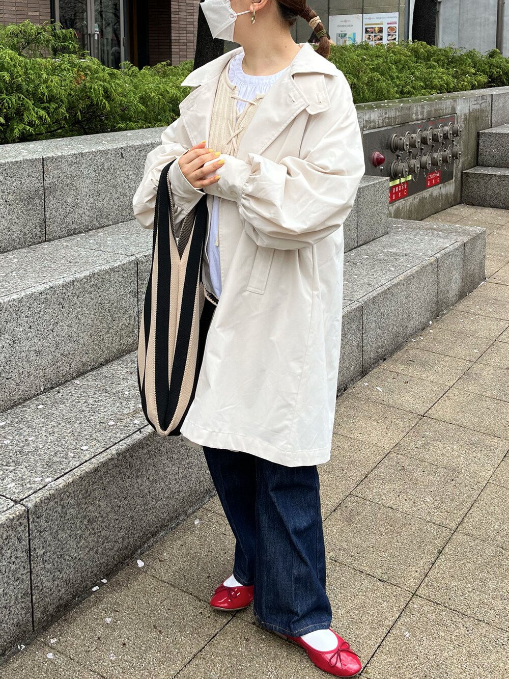 ブルー系のパンツ、ホワイト系のトレンチコート、レッド系のバレエシューズを着用したレディースの春コーディネートの2枚目の写真