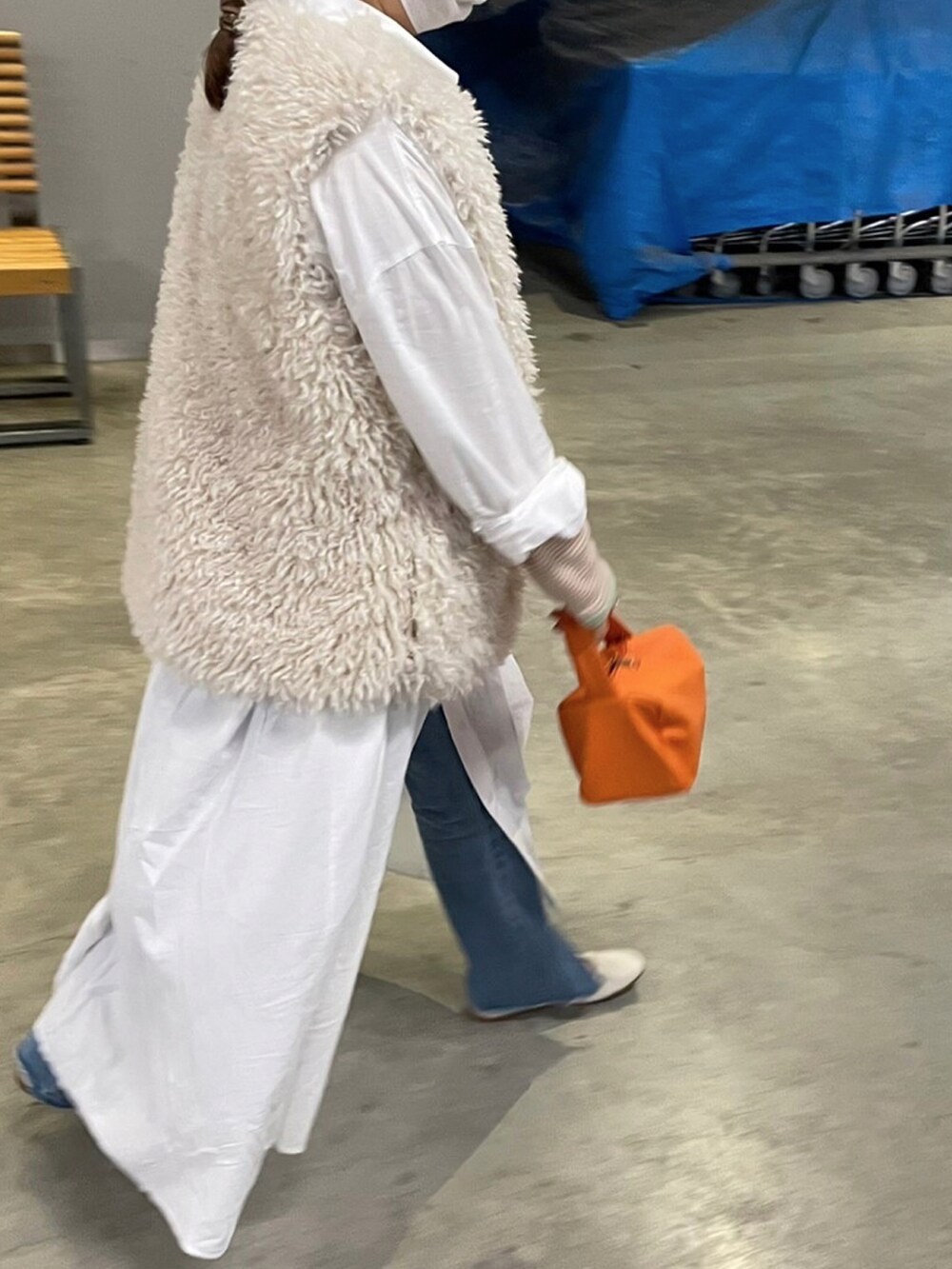 ホワイト系のシャツワンピース、オレンジ系のハンドバッグ、ホワイト系のベストを着用したレディースの春コーディネートの2枚目の写真