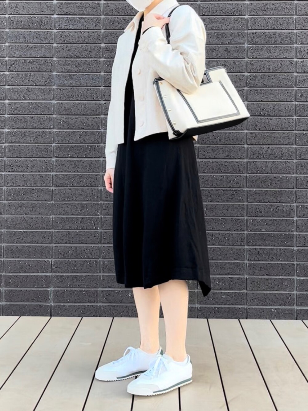 ホワイト系のジャケット/アウター、ホワイト系のバッグ、ブラック系のワンピースを着用したレディースの冬コーディネートの2枚目の写真