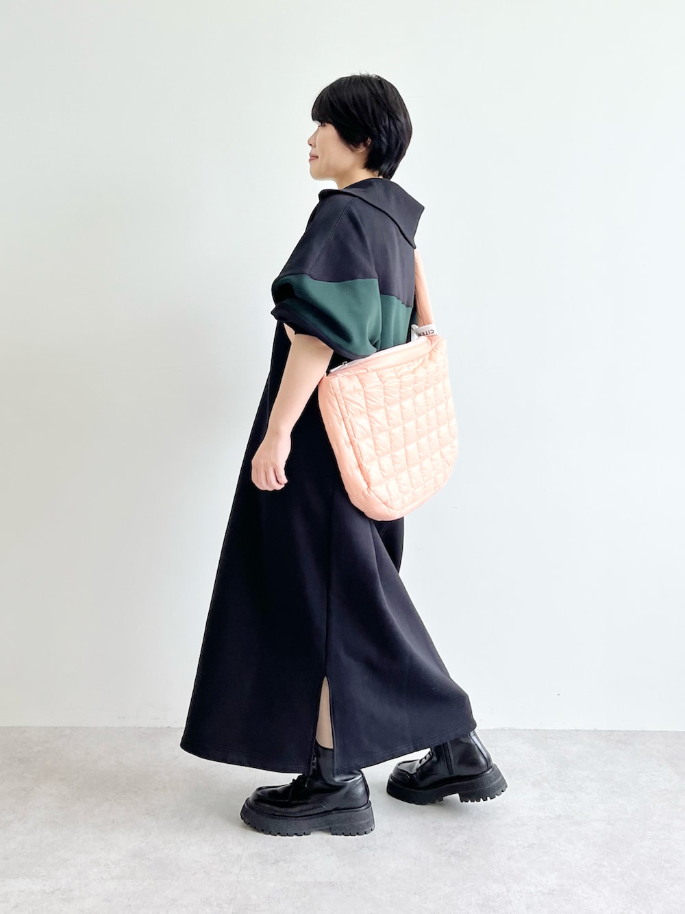 ブラック系のワンピース、ブラック系のブーツ、ピンク系のショルダーバッグを着用したレディースの夏コーディネートの2枚目の写真