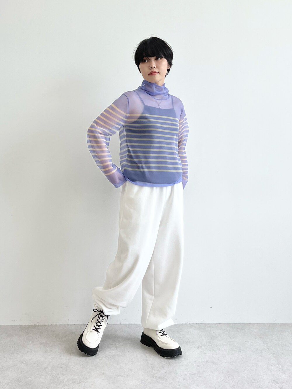 ブルー系のニット/セーター、ホワイト系のスウェットパンツ、ホワイト系のブーツを着用したレディースの夏コーディネートの2枚目の写真