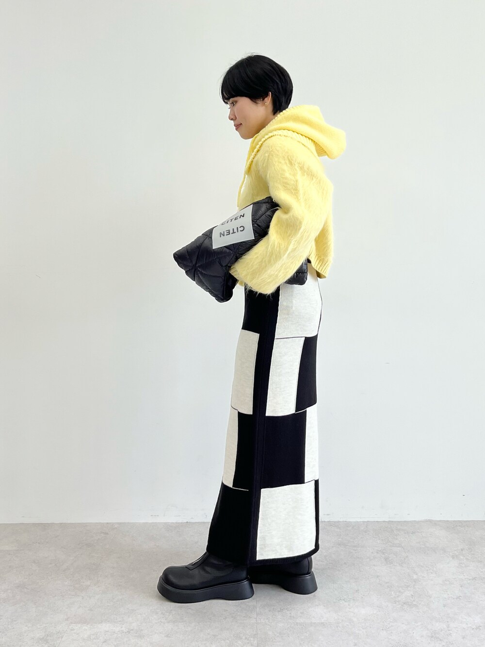 ベージュ系のニット/セーター、ブラック系のスカート、ブラック系のトートバッグを着用したレディースの秋コーディネートの2枚目の写真