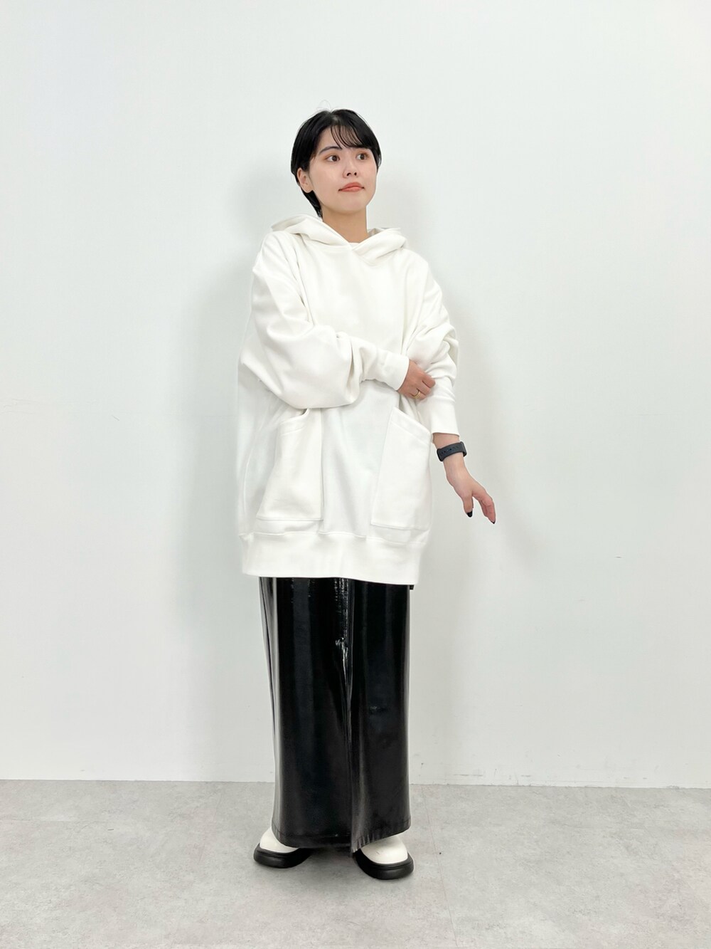 ホワイト系のパーカー、ブラック系のスカート、ホワイト系のブーツを着用したレディースの秋コーディネートの3枚目の写真