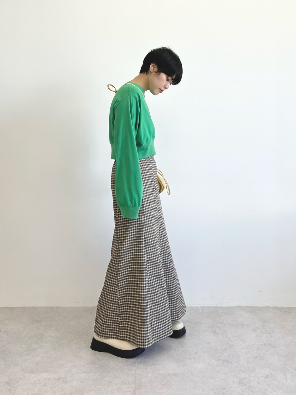 グリーン系のトップス、ベージュ系のショルダーバッグ、ブラウン系のスカートを着用したレディースの夏コーディネートの3枚目の写真