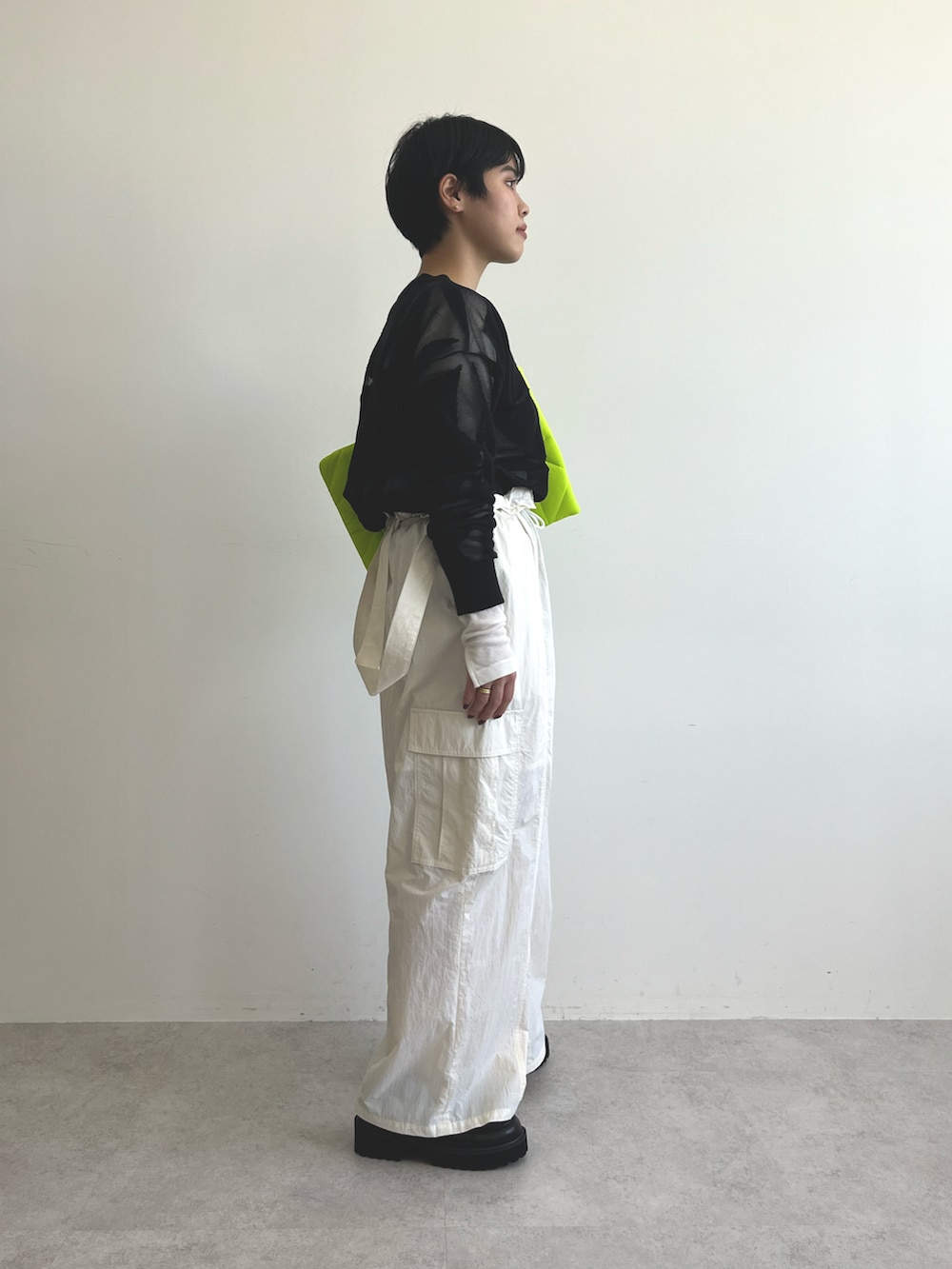 ブラック系のニット/セーター、ホワイト系のTシャツ/カットソー、ホワイト系のカーゴパンツを着用したレディースの冬コーディネートの2枚目の写真