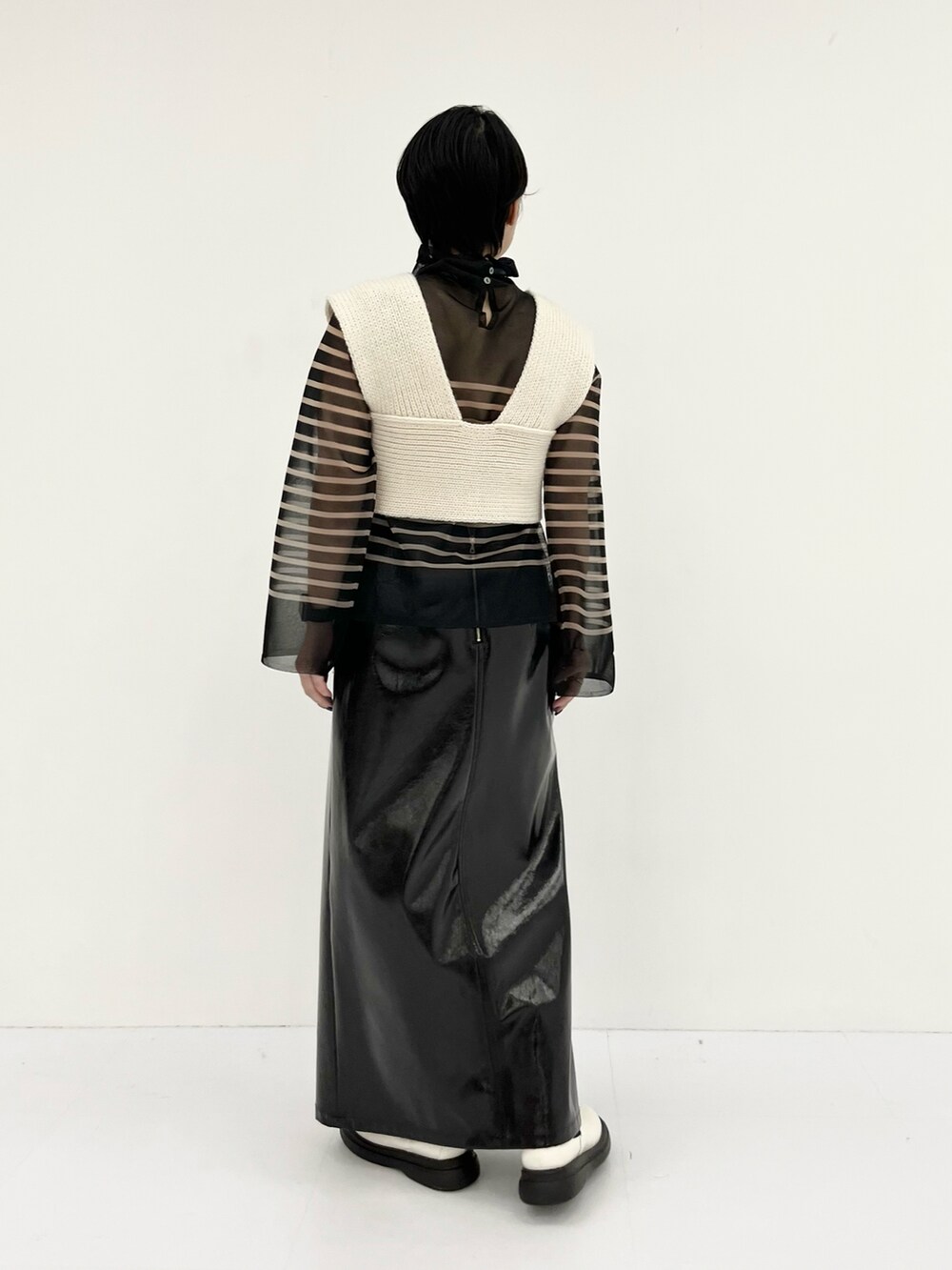 ホワイト系のベスト、ブラック系のニット/セーター、ブラック系のスカートを着用したレディースの秋コーディネートの3枚目の写真