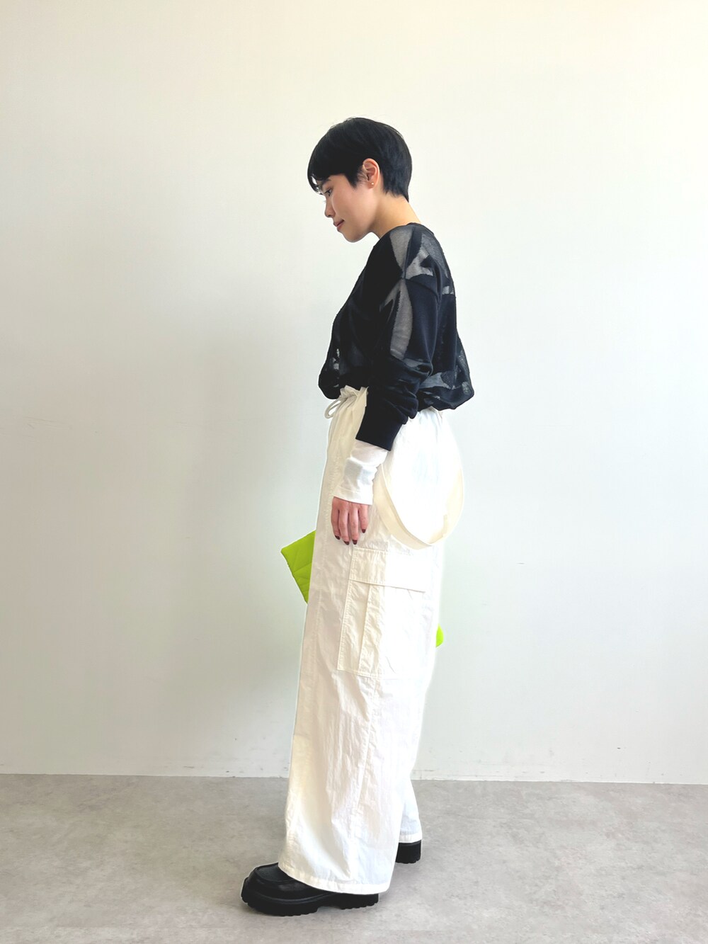 ブラック系のニット/セーター、ホワイト系のTシャツ/カットソー、ホワイト系のカーゴパンツを着用したレディースの冬コーディネートの3枚目の写真