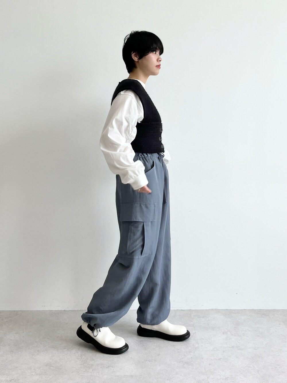 ブラック系のベスト、ホワイト系のTシャツ/カットソー、ブルー系のカーゴパンツを着用したレディースの夏コーディネートの2枚目の写真