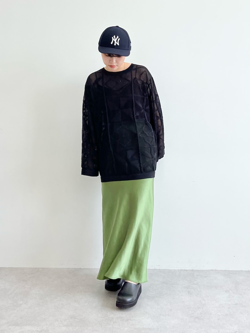 ブラック系のニット/セーター、グリーン系のスカート、ブラック系のその他シューズを着用したレディースの夏コーディネートの2枚目の写真