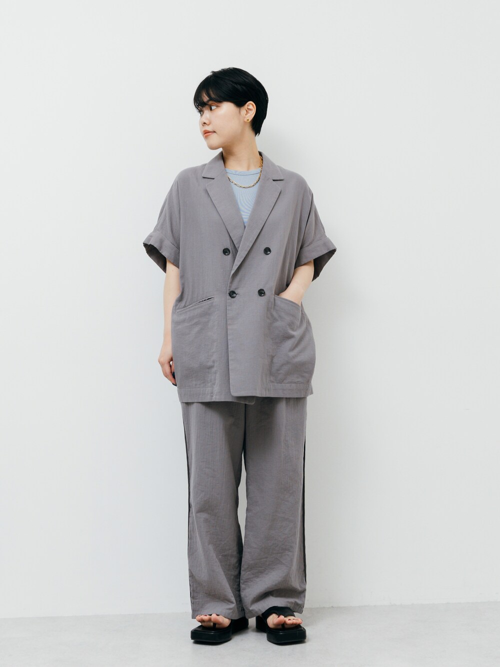 グレー系のパンツ、ブラック系のサンダル、グレー系のその他アウターを着用したレディースの夏コーディネートの2枚目の写真