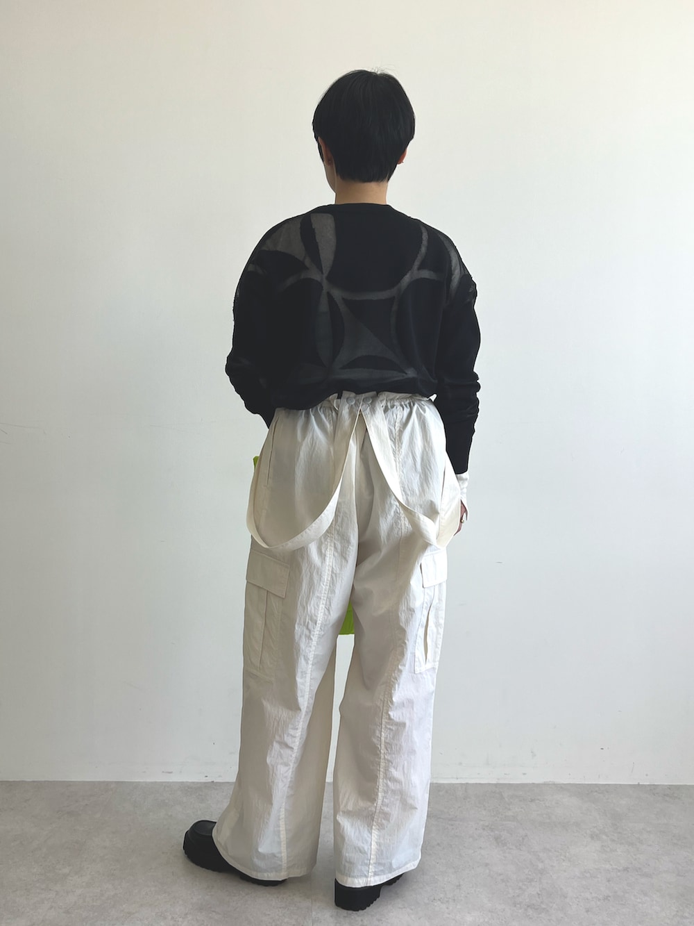 ブラック系のニット/セーター、ホワイト系のTシャツ/カットソー、ホワイト系のカーゴパンツを着用したレディースの冬コーディネートの4枚目の写真