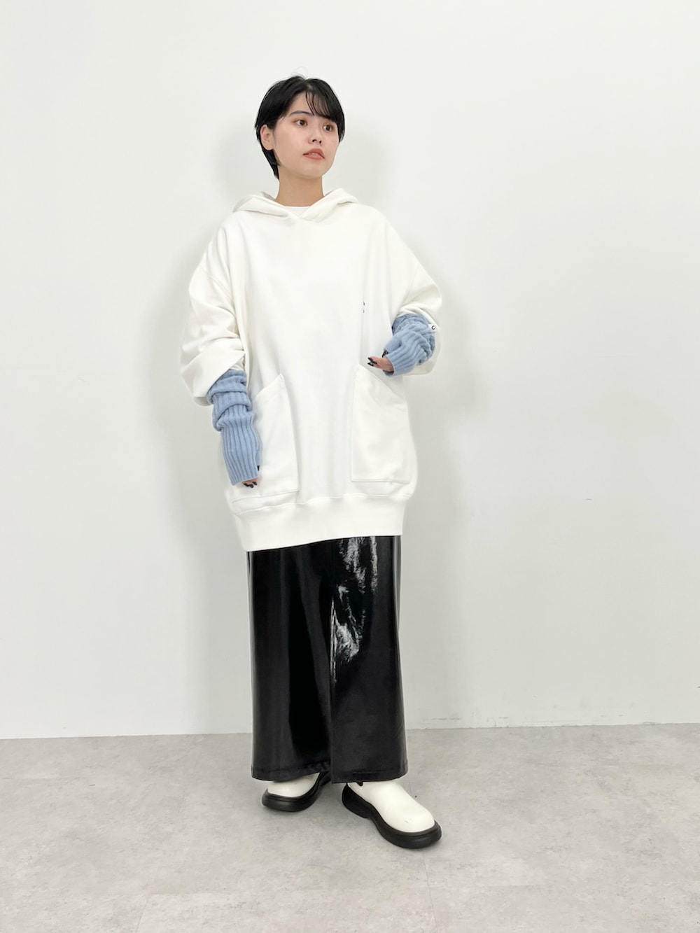 ホワイト系のパーカー、ブラック系のスカート、ホワイト系のブーツを着用したレディースの秋コーディネートの2枚目の写真